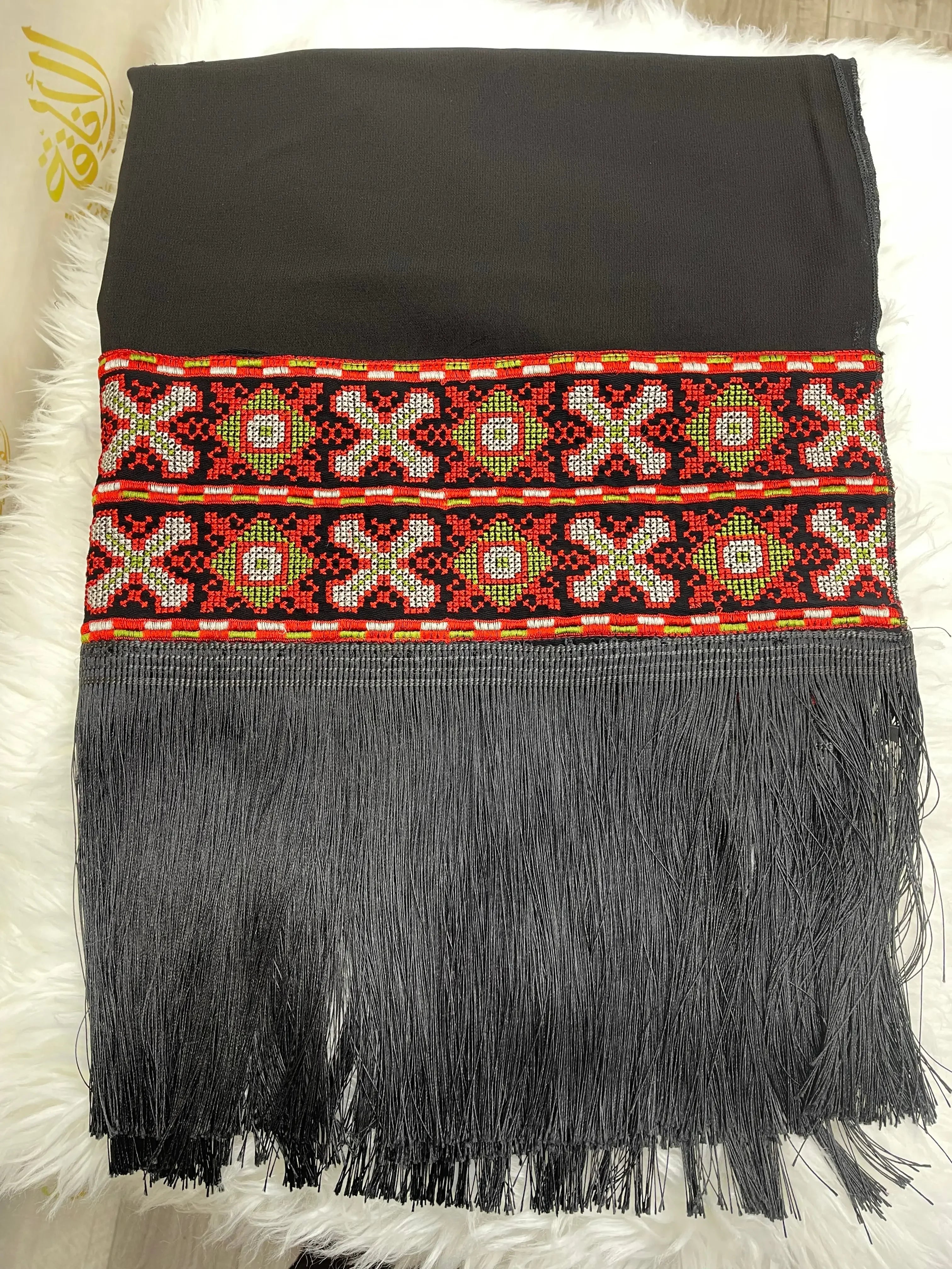 Palestinian embroidered shawl with detailed red and green geometric patterns and black fringe edges