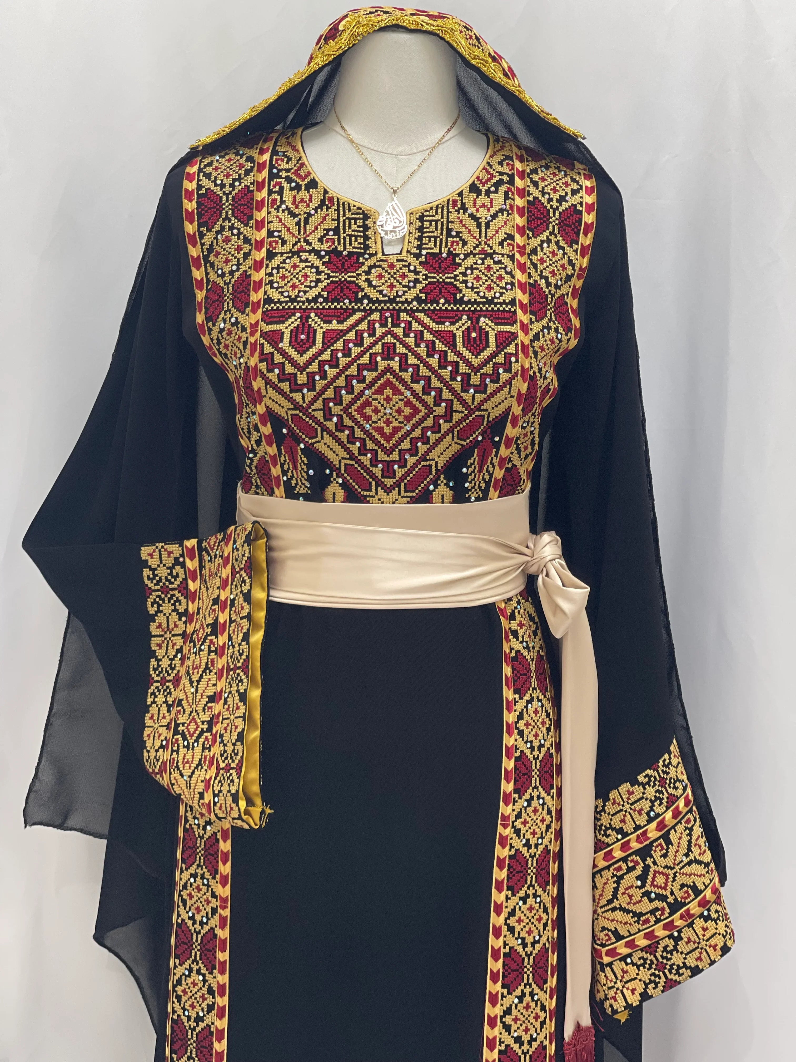 Palestinian embroidered thoub in black with intricate red and gold embroidery and beige waist sash