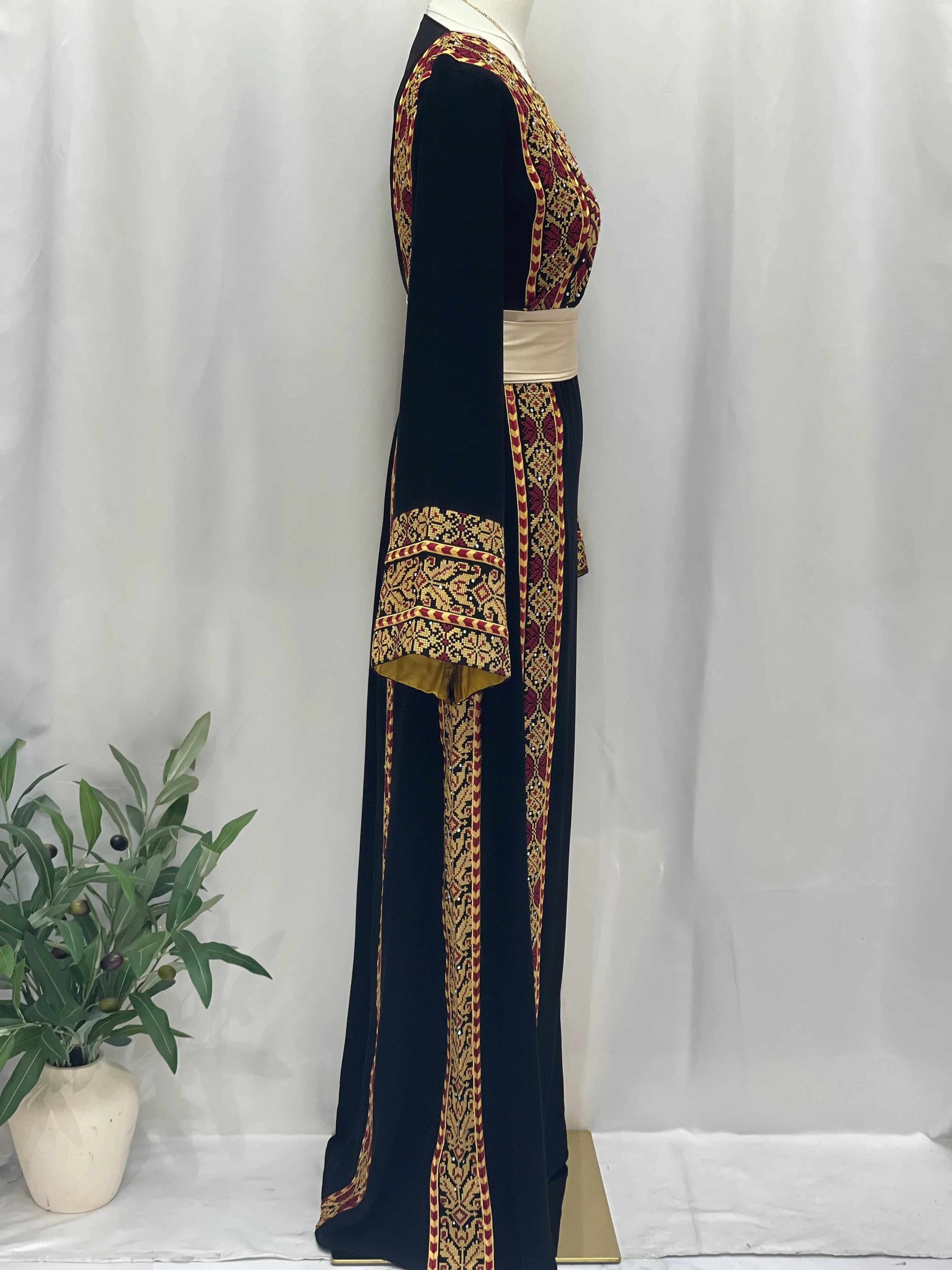 Palestinian embroidered thoub in black with intricate red and gold embroidery displayed on mannequin