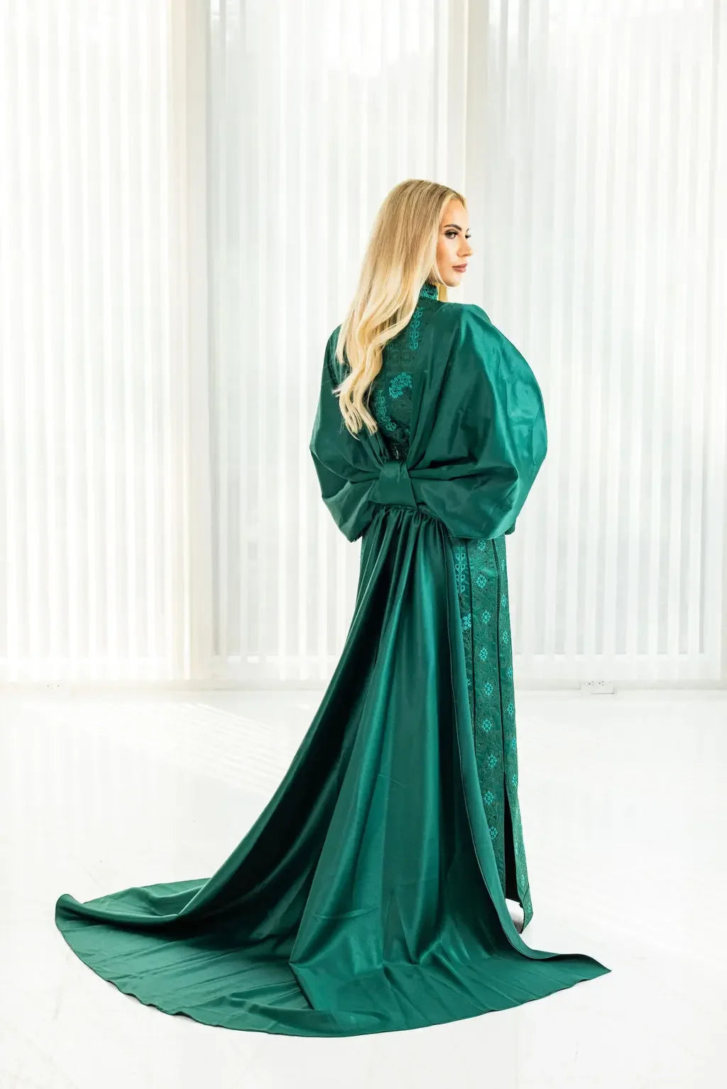 Green satin bridal dress with cape featuring detailed Palestinian Elegance embroidery on flowing fabric