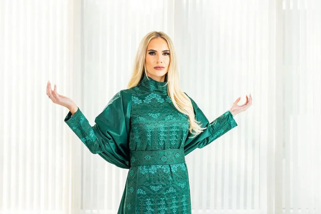Green satin bridal dress with cape featuring intricate embroidery from Palestinian Elegance